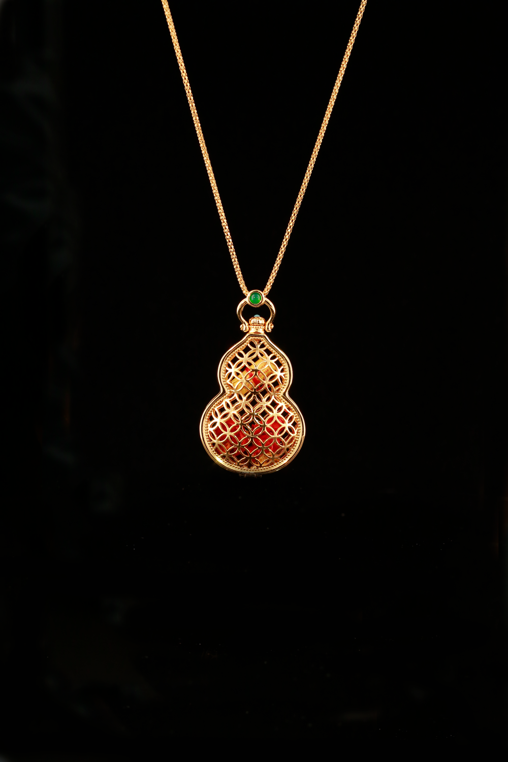 Fulu Cangbao gourd-shaped openwork locket with a red interior and green top accent on a black background