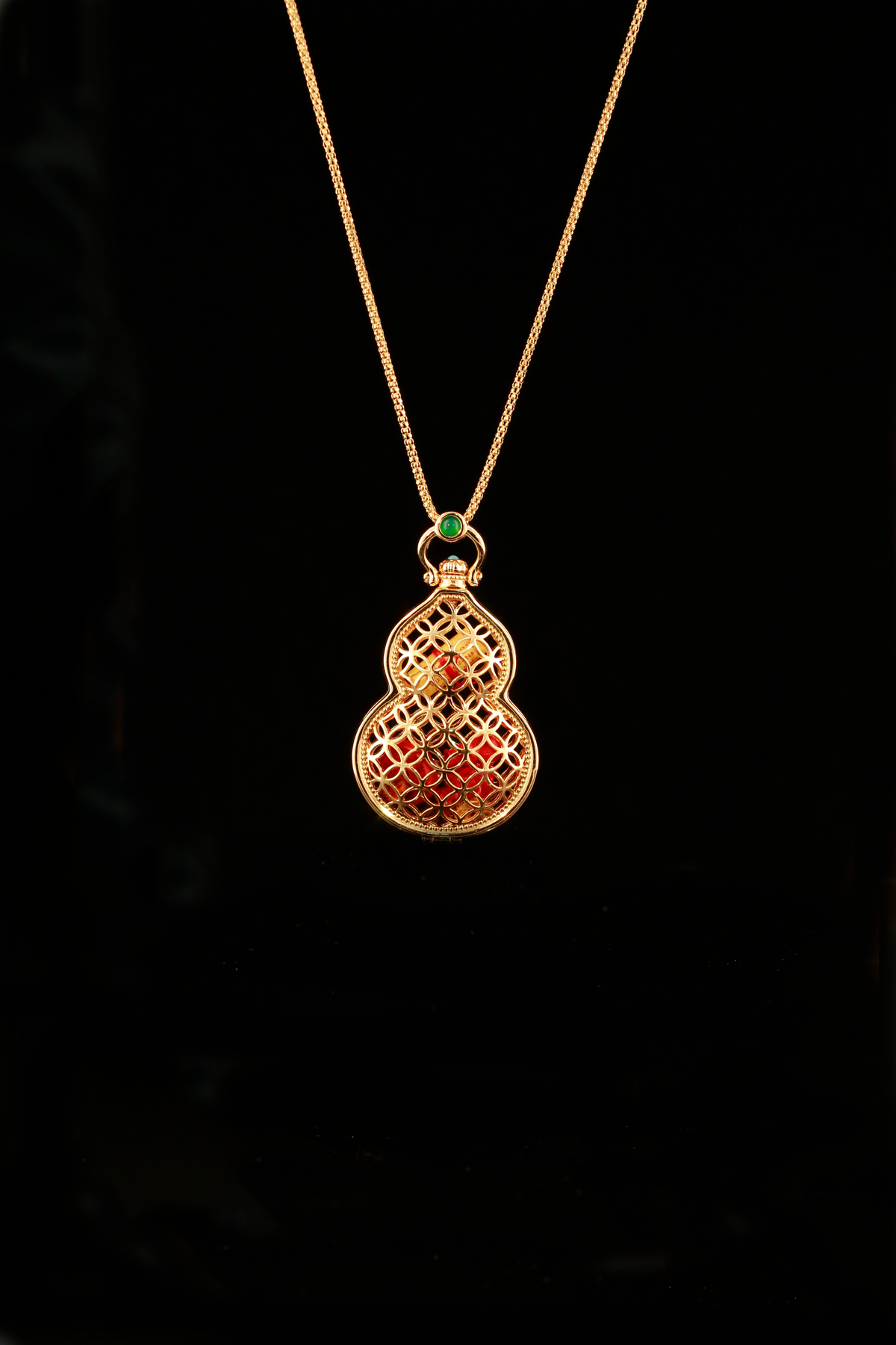 Fulu Cangbao gourd-shaped openwork locket with a red interior and green top accent on a black background