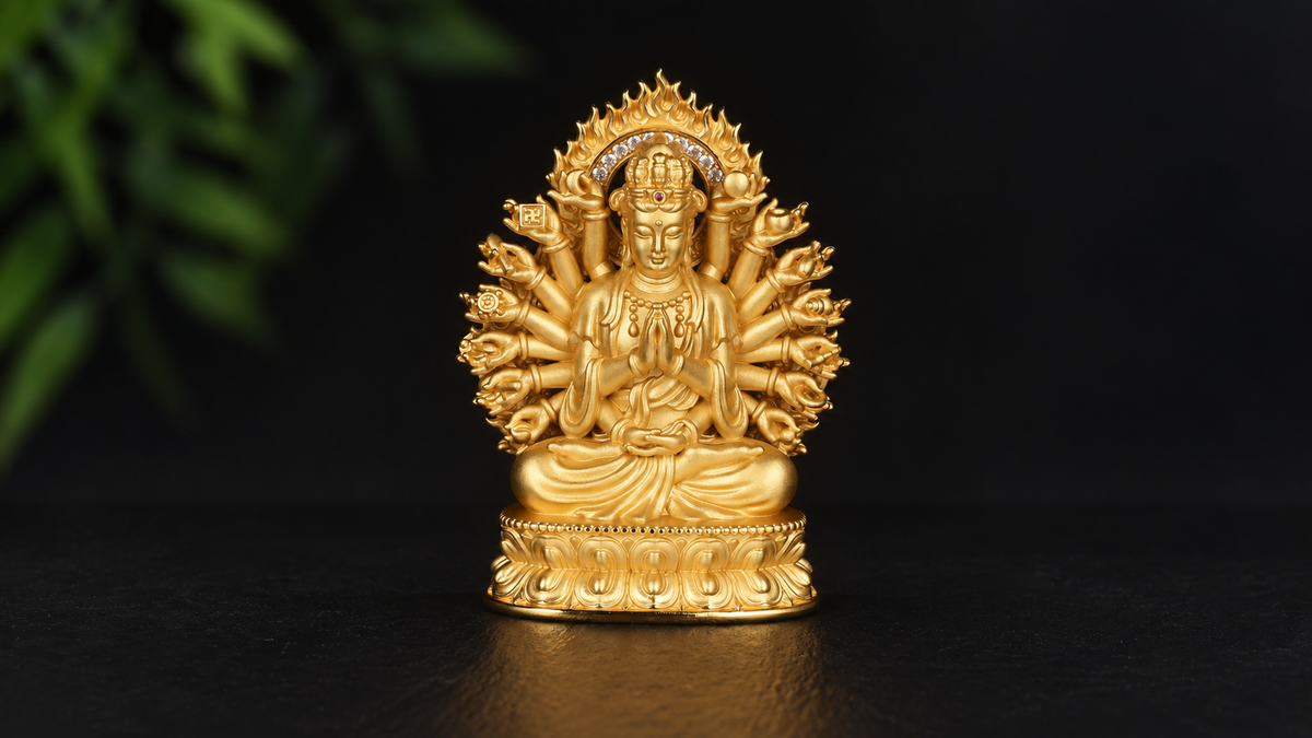 Gold-tone Thousand-Armed Guanyin sculpture with central prayer hands, a fan of arms, multiple heads, flame-shaped aureole, and a layered lotus base against a black background.