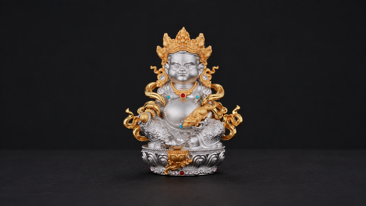 Silver-tone seated Yellow Jambhala figure with gold-tone crown, mongoose-like attribute, and lotus-style pedestal fully visible against a dark background.