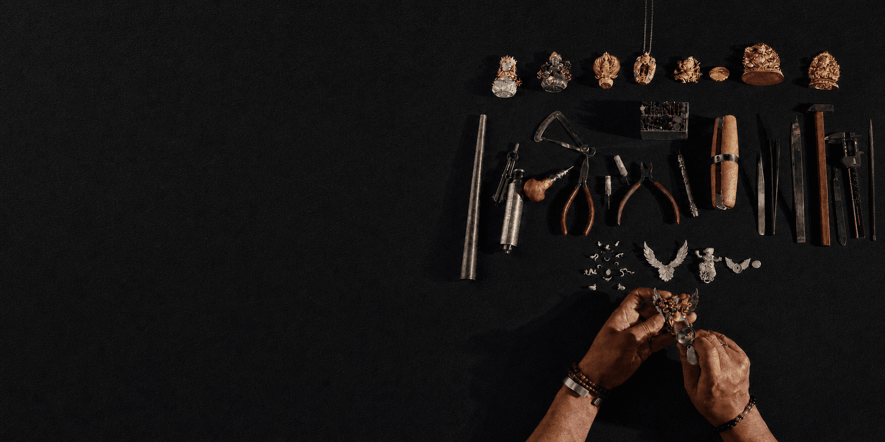 LIKREAT jewelry objects and hand-carving tools arranged on black cloth