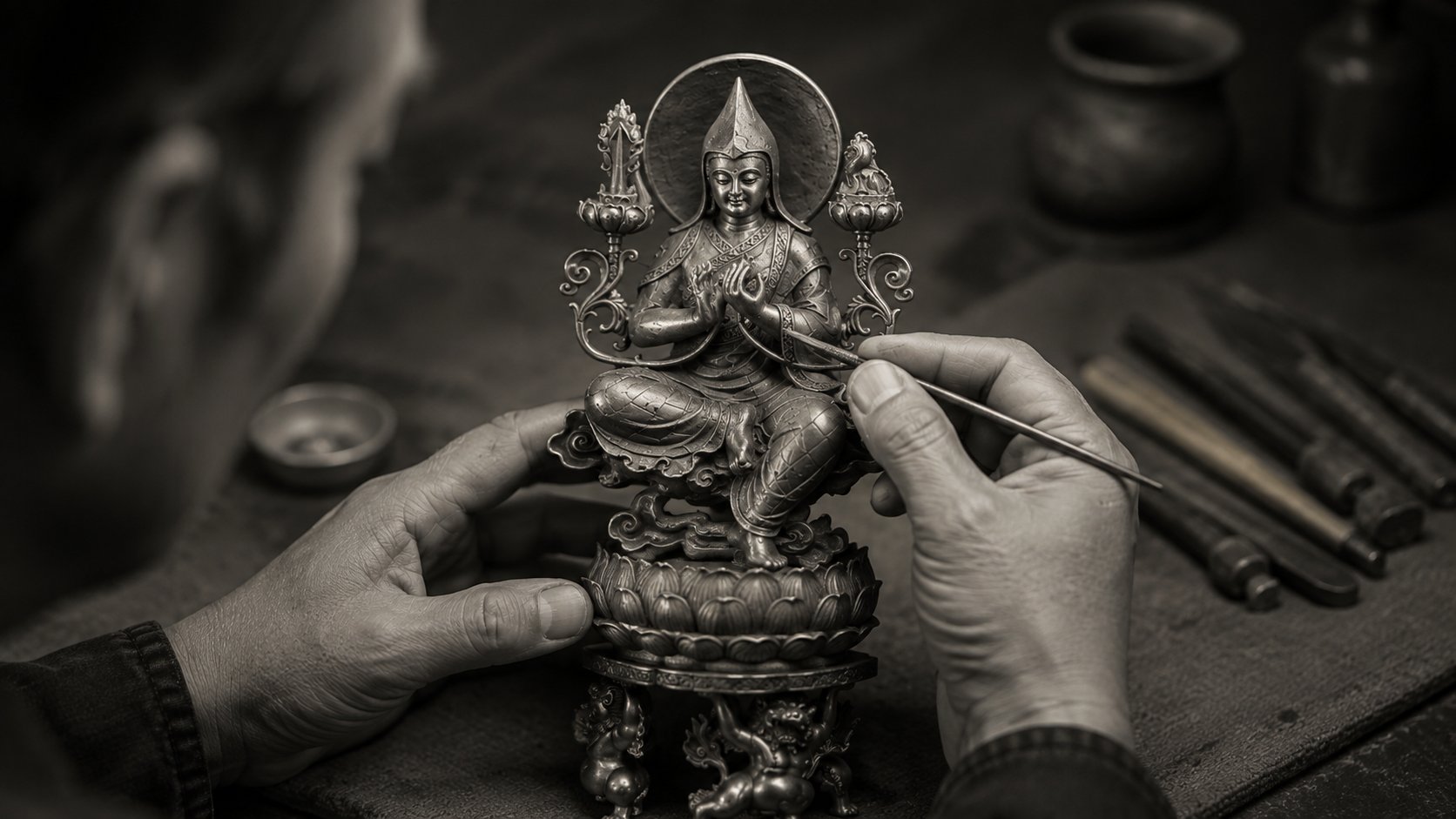 Hands examining the surface and relief of a Je Tsongkhapa sculpture